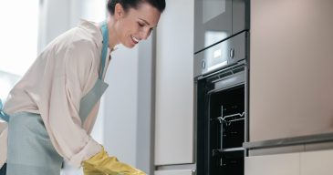 Kitchen work. Young dark-haired woman cleaning kitchen appliances